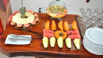 Una mesa de madera con diversas frutas y un bol de ensalada de frutas.