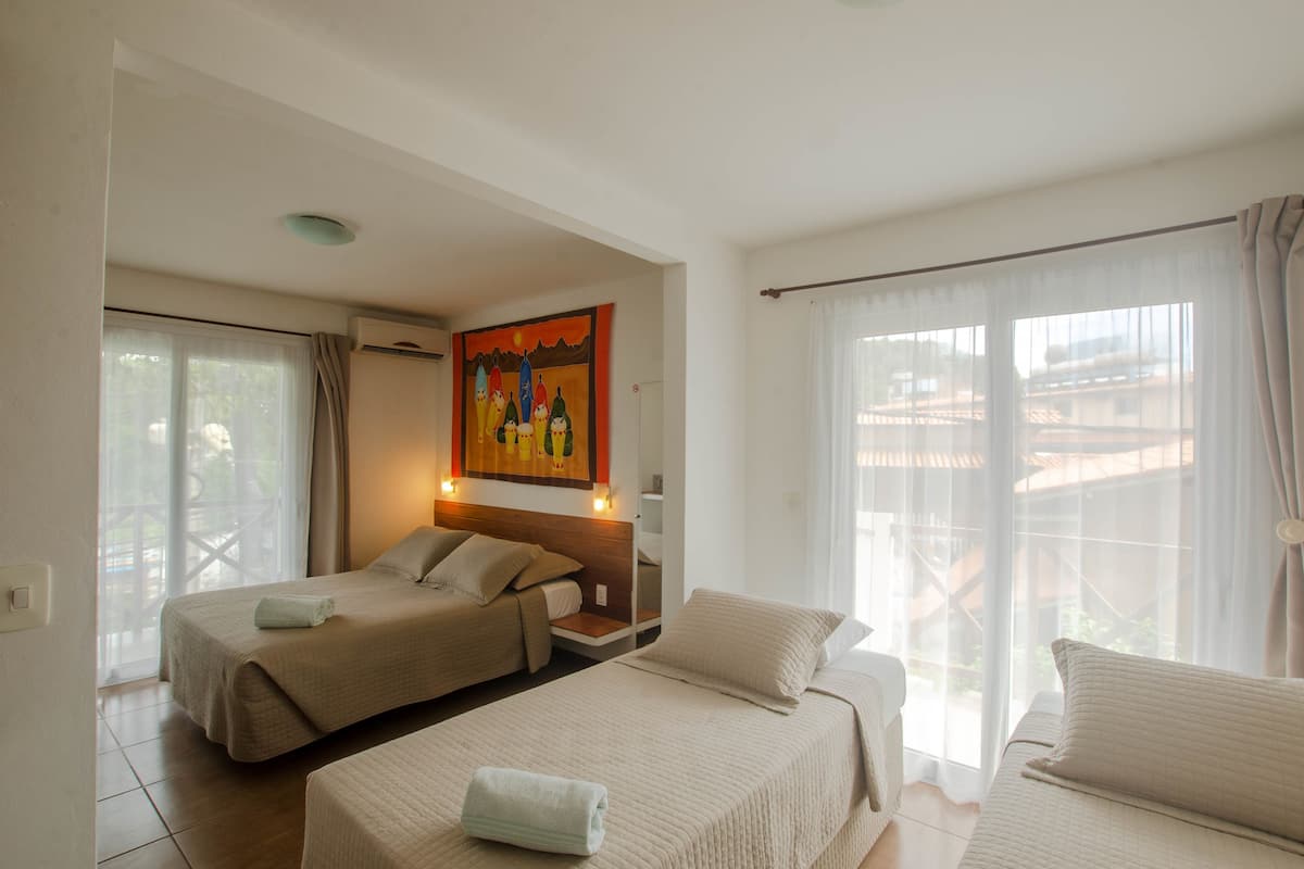 Une chambre d’hôtel avec deux lits, un tableau au mur et une vue sur l’extérieur.
