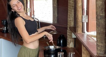 Una persona cocinando en una cocina rústica con paredes de madera y una ventana.
