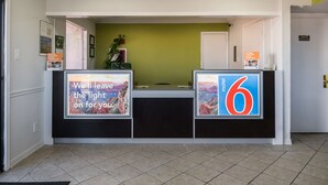 Un comptoir d’accueil agrémenté d’un mur végétal et de deux grands panneaux : l’un représente un paysage au coucher du soleil, l’autre affiche le chiffre 6.