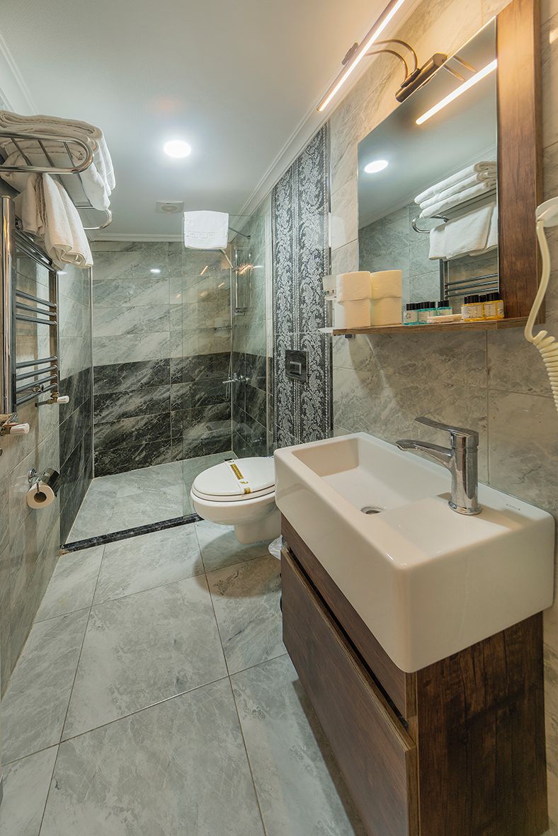 A modern bathroom with a glass-enclosed shower, a white sink, and a marble-tiled shower area.
