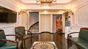 A lobby with a chandelier, a staircase, and two green upholstered chairs. - Beyazit Palace Hotel (Istanbul)