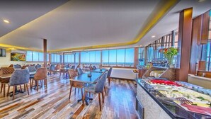A spacious dining area with multiple tables and chairs, large windows offering a view, and a bar area with various items. - Beyazit Palace Hotel (Istanbul)