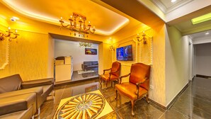 A lobby with a chandelier, leather chairs, a TV, and a patterned floor. - Beyazit Palace Hotel (Istanbul)