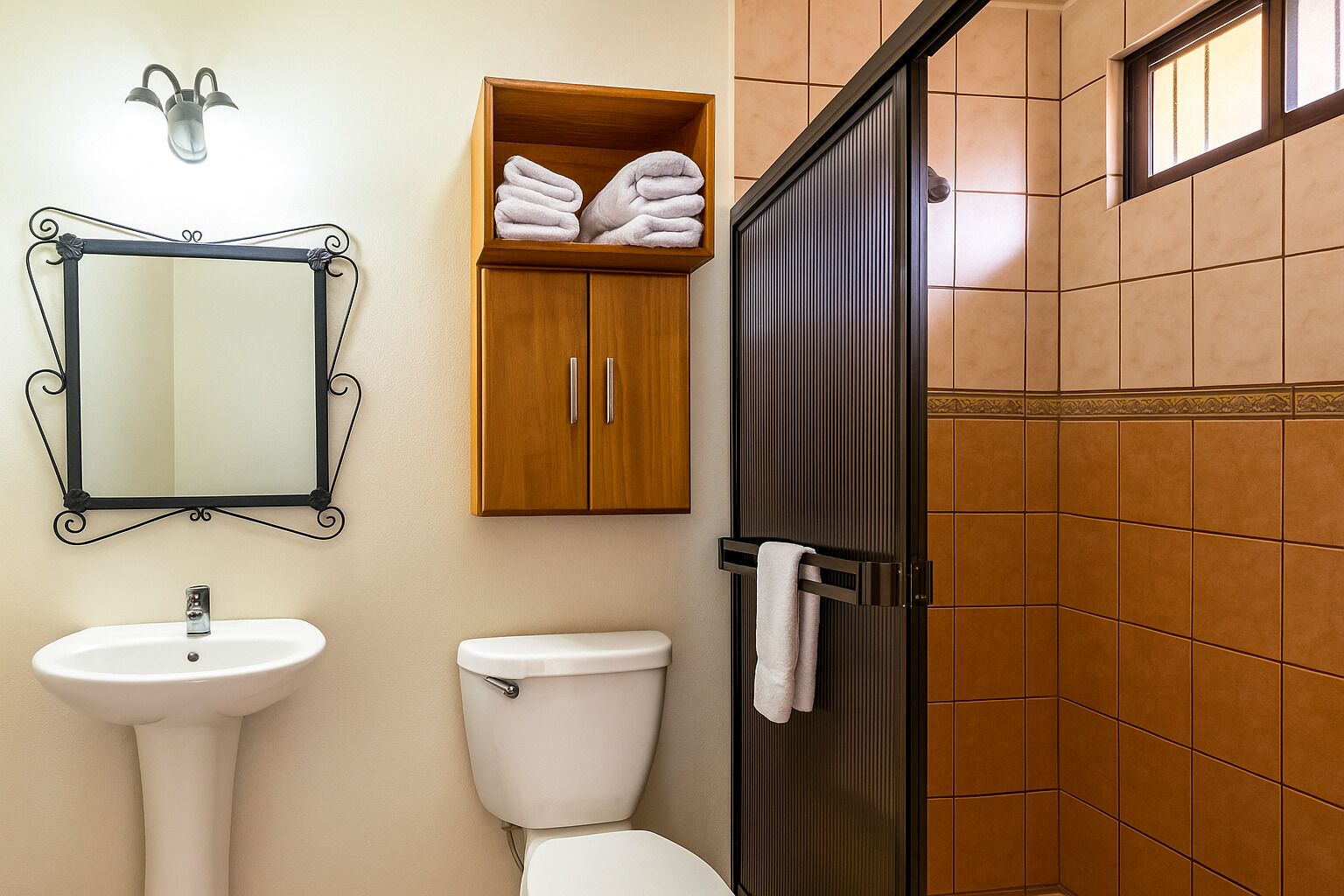 Casa de banho com lavatório, sanita e armário com toalhas.
