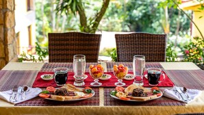 Een eettafel gedekt met borden eten, glazen water en thee, en bestek.