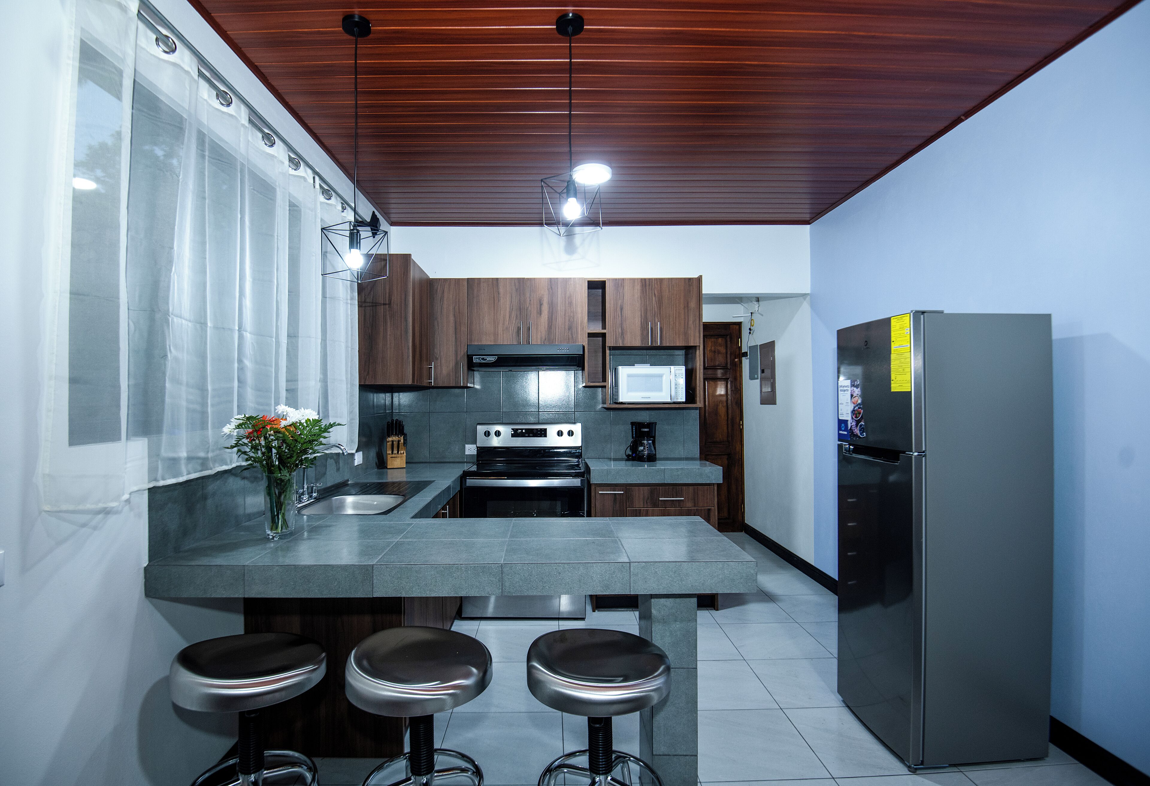 Una cocina moderna con una isla central, electrodomésticos de acero inoxidable y armarios de madera.