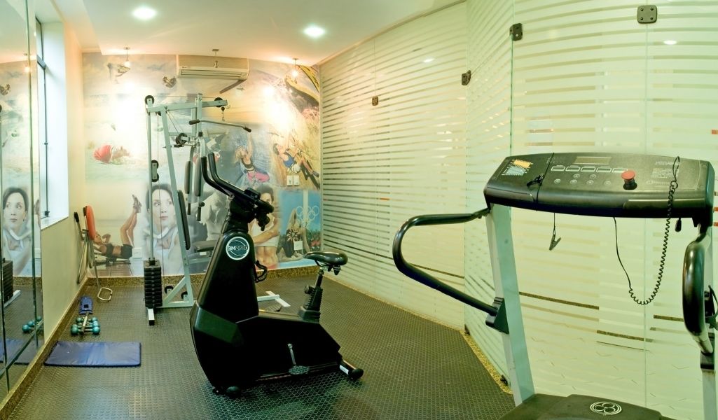 Ein Fitnessraum mit Trainingsgeräten, Laufband und einer Wand mit Wandgemälde.