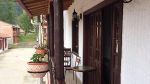 A covered outdoor area with a wooden railing, a table, chairs, and hanging flower pots. - Fami Hotel Vive Jardin - Hostel (Jardin)