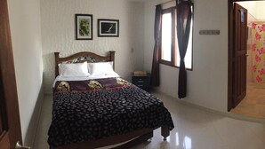 A bedroom with a bed, a window with curtains, a door leading to another room, and a wall-mounted power outlet. - Fami Hotel Vive Jardin - Hostel (Jardin)