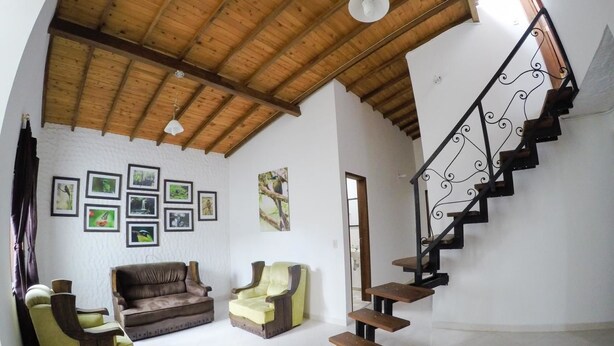 A spacious living area with a wooden ceiling, a staircase with a wrought iron railing, and a sofa set. - Fami Hotel Vive Jardin - Hostel (Jardin)