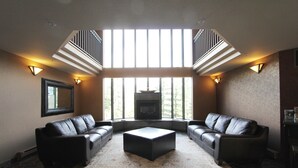 A spacious living room with a stone floor, two leather sofas, a central ottoman, and a fireplace. - Marquise Condos by Whistler Retreats (Whistler)