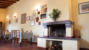Un coin repas agrémenté d’une cheminée, de chaises et de tables en bois.