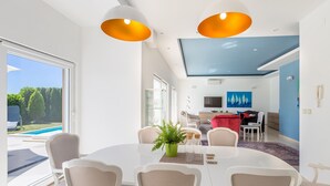 A modern dining area with a large table, chairs, and pendant lighting. - Villa Sv. Petar (Opatija)