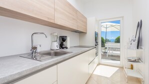 A modern kitchen with a built-in sink, a coffee maker, and a window overlooking a balcony. - Villa Sv. Petar (Opatija)