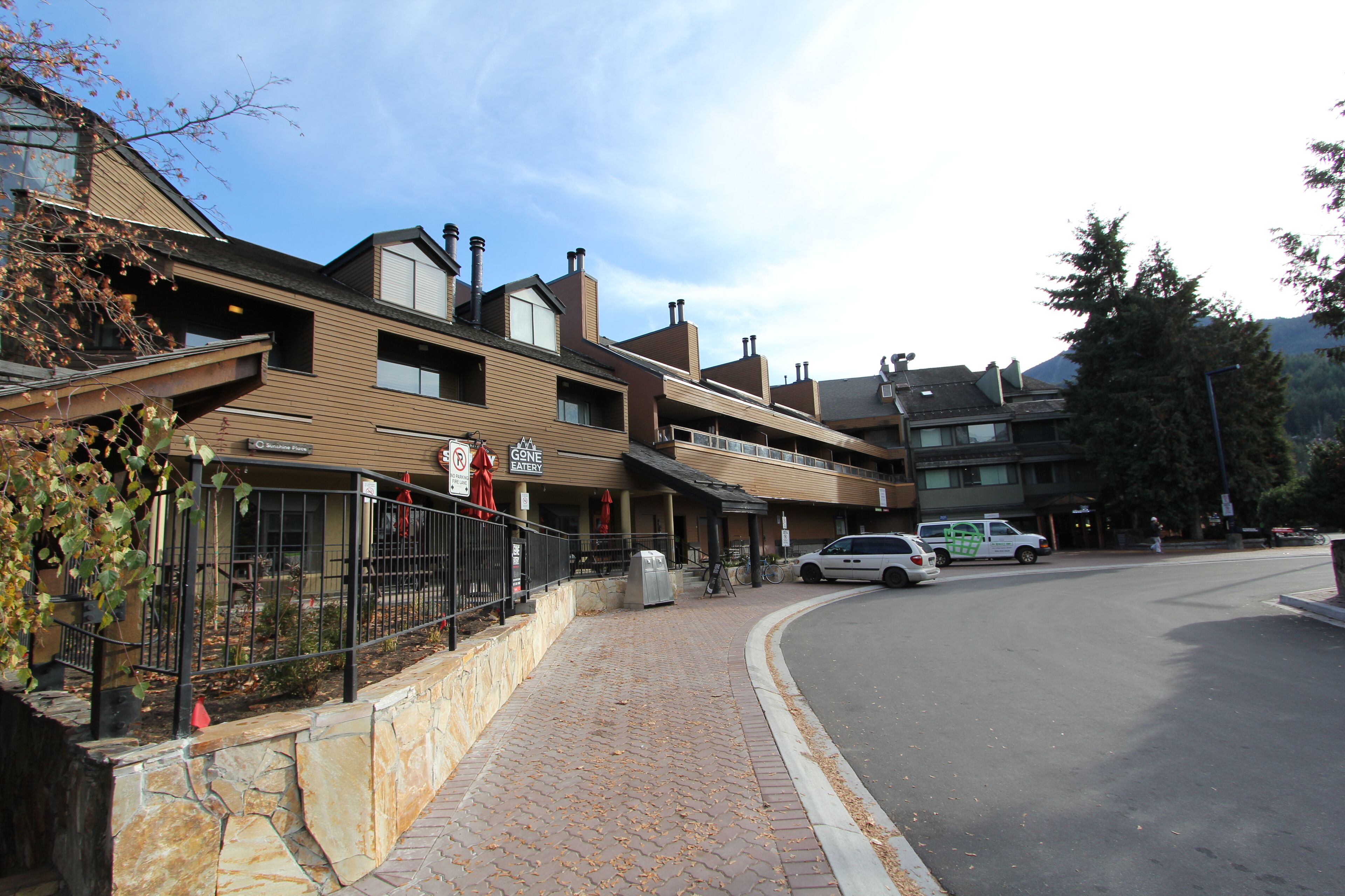A multi-story building with a stone base, a wooden upper level, and a metal fence.