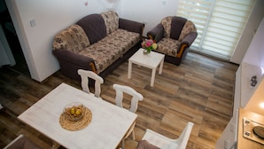 Una sala de estar moderna con un conjunto de sofá, una mesa de comedor con sillas y una mesita blanca.