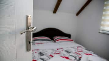 A room with a bed, a door with a handle, and a window with blinds.