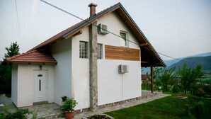Una casa de una sola planta con techo inclinado, base de piedra y puerta frontal de madera.