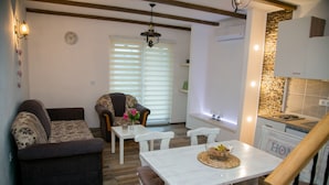 Una sala de estar acogedora con un sofá, una mesa de comedor con sillas y una zona de cocina con mostrador.