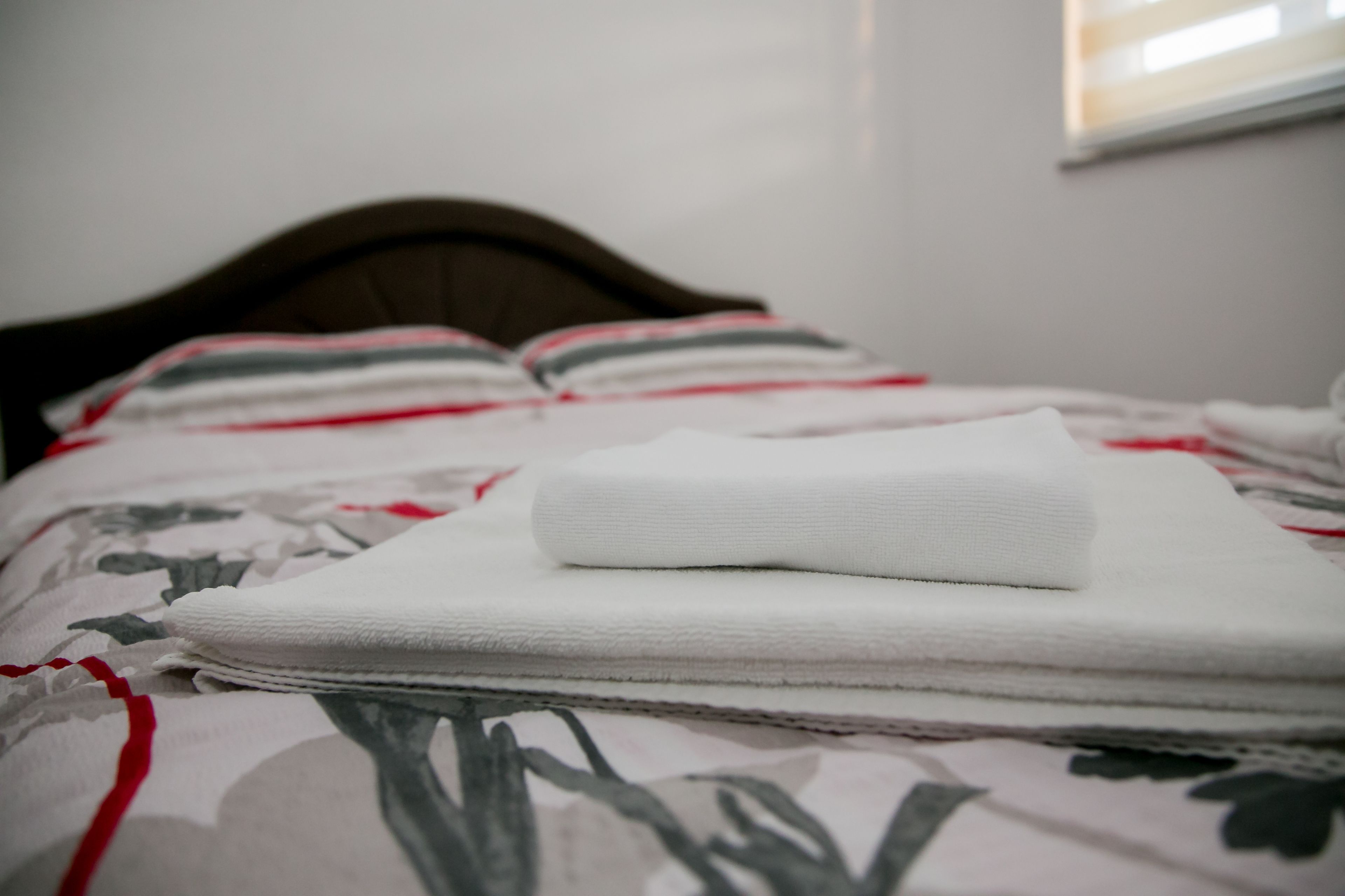 A neatly made bed with a floral-patterned bedspread and a folded white towel on top.