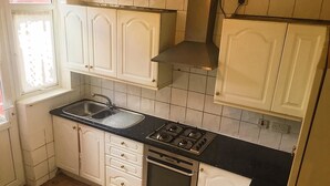 Una cocina con armarios blancos, encimera negra, estufa de acero inoxidable y un lavamanos.