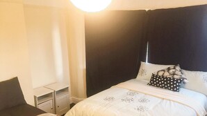 Un dormitorio con cama, mesita de noche y una silla.