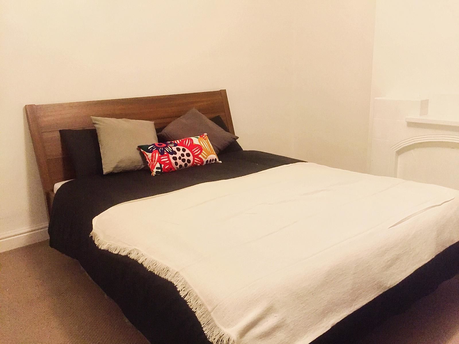 Ein Bett mit Holzvorhang, schwarz-weißer Bettwäsche und bunten Kissen.