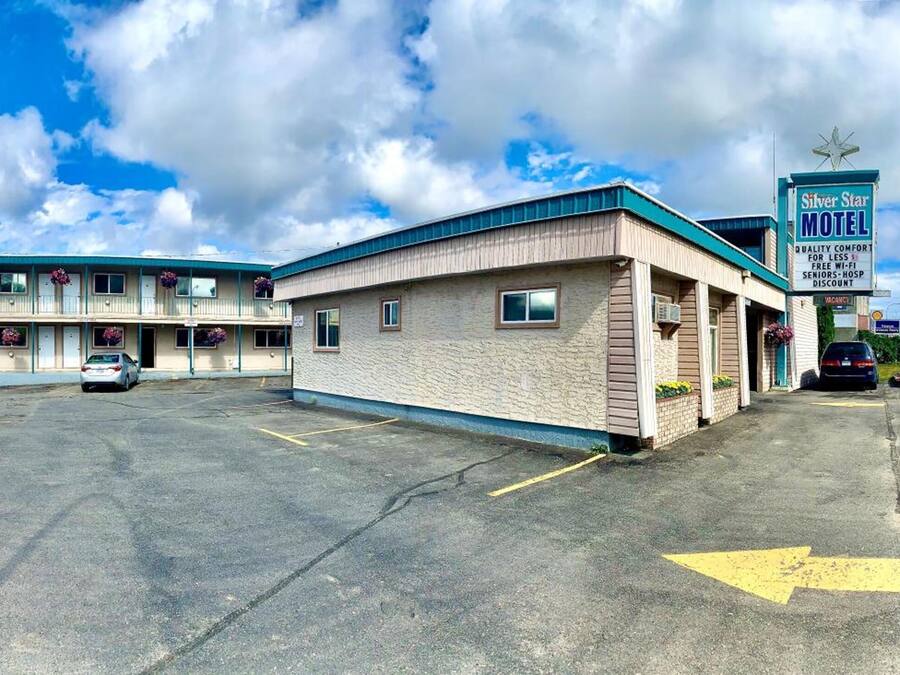 A motel with a sign reading "Silver Star Motel" and a parking lot with several cars.