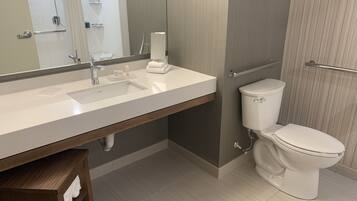 A modern bathroom with a large mirror, a white sink, a toilet, and a towel rack.