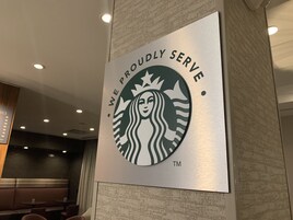 Un letrero de Starbucks con el texto 'Servimos con orgullo' y el logotipo de Starbucks.
