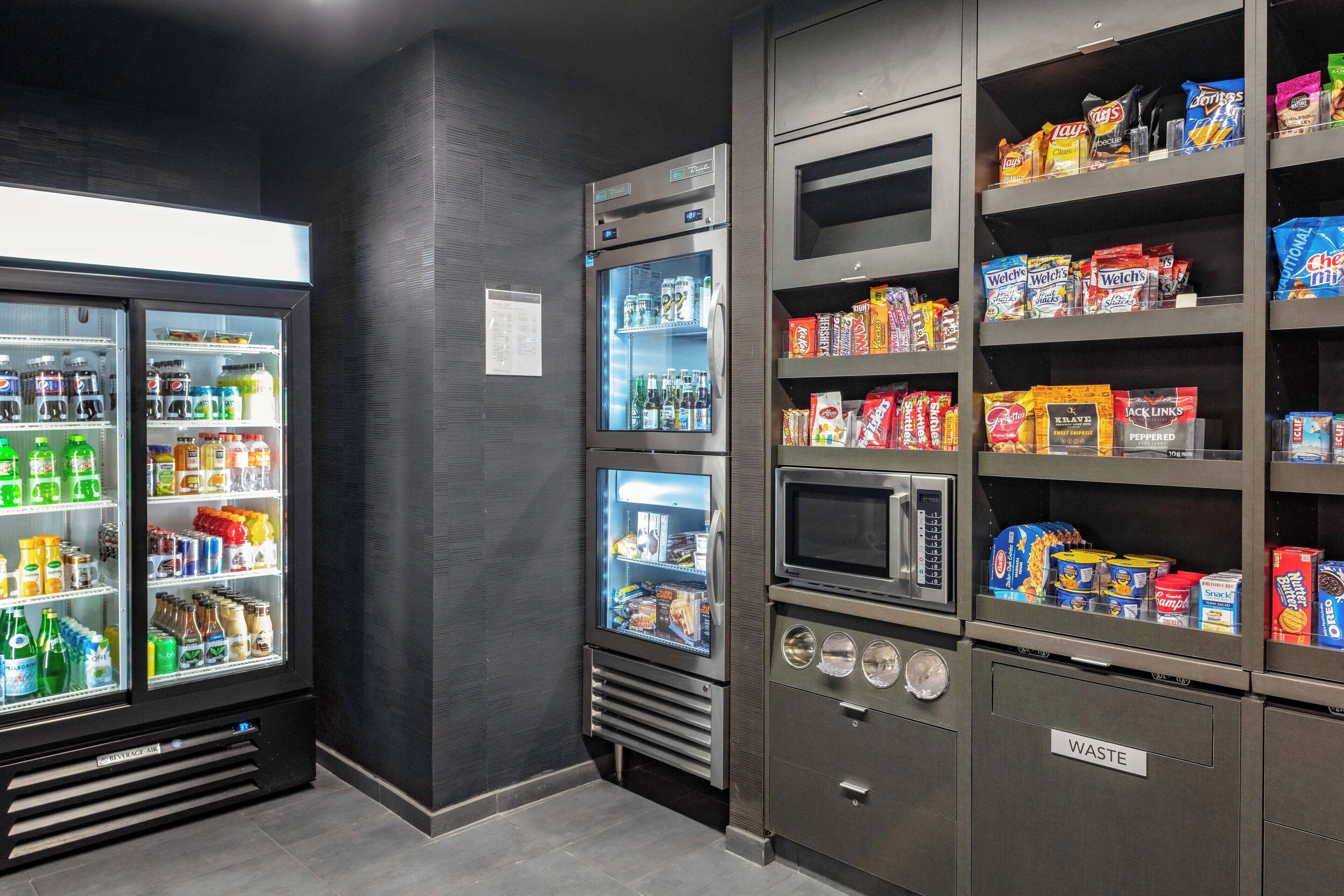 A vending machine area with snacks and drinks, a microwave, and a waste bin.