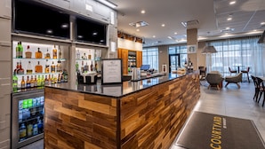 Eine moderne Bar mit einer Holztresen, einer Kühlanlage und einer Sitzgelegenheit mit Tischen und Stühlen.