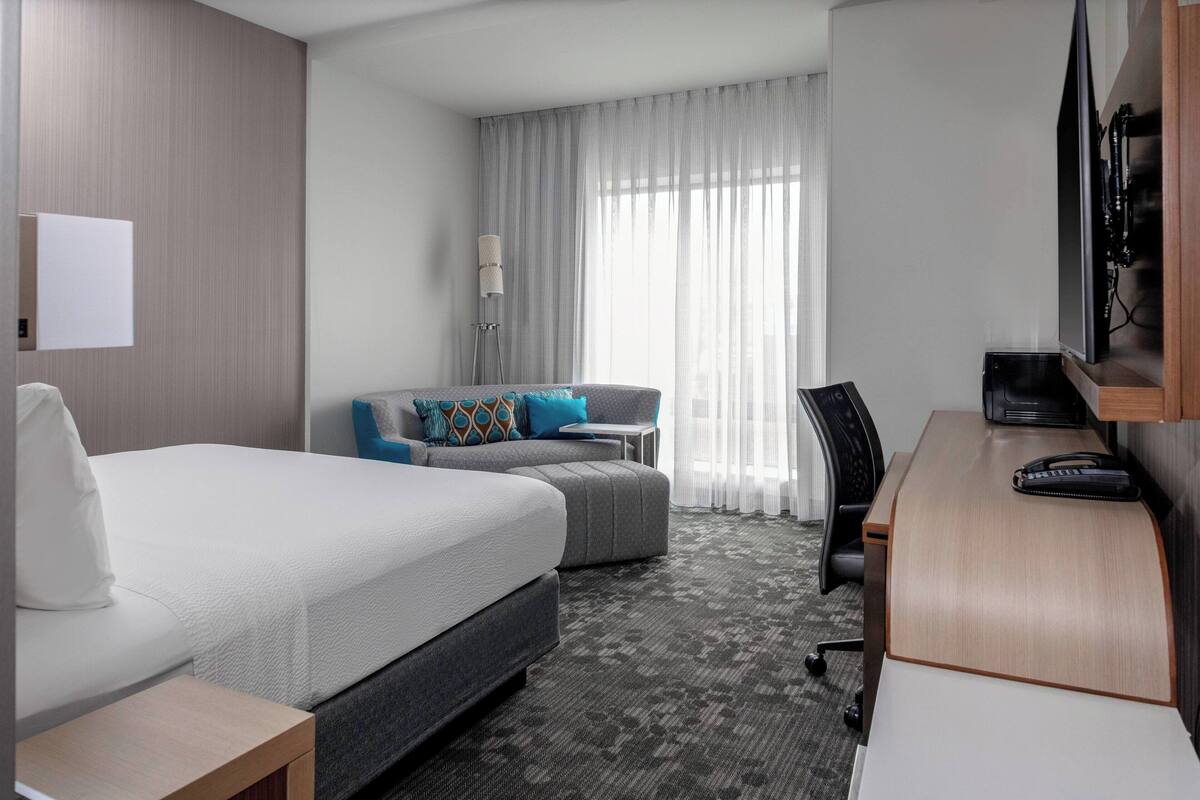 A hotel room with a bed, a sofa, a desk, and a chair.