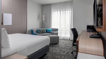 A hotel room with a bed, a sofa, a desk, and a chair.