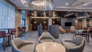 Eine moderne Lobby mit runden Tischen, bequemen Sitzgelegenheiten und einem großen Kronleuchter.