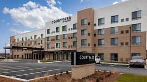 Ein Hotel der Courtyard by Marriott mit modernem Design, inklusive Parkplatz und blauem Himmel.