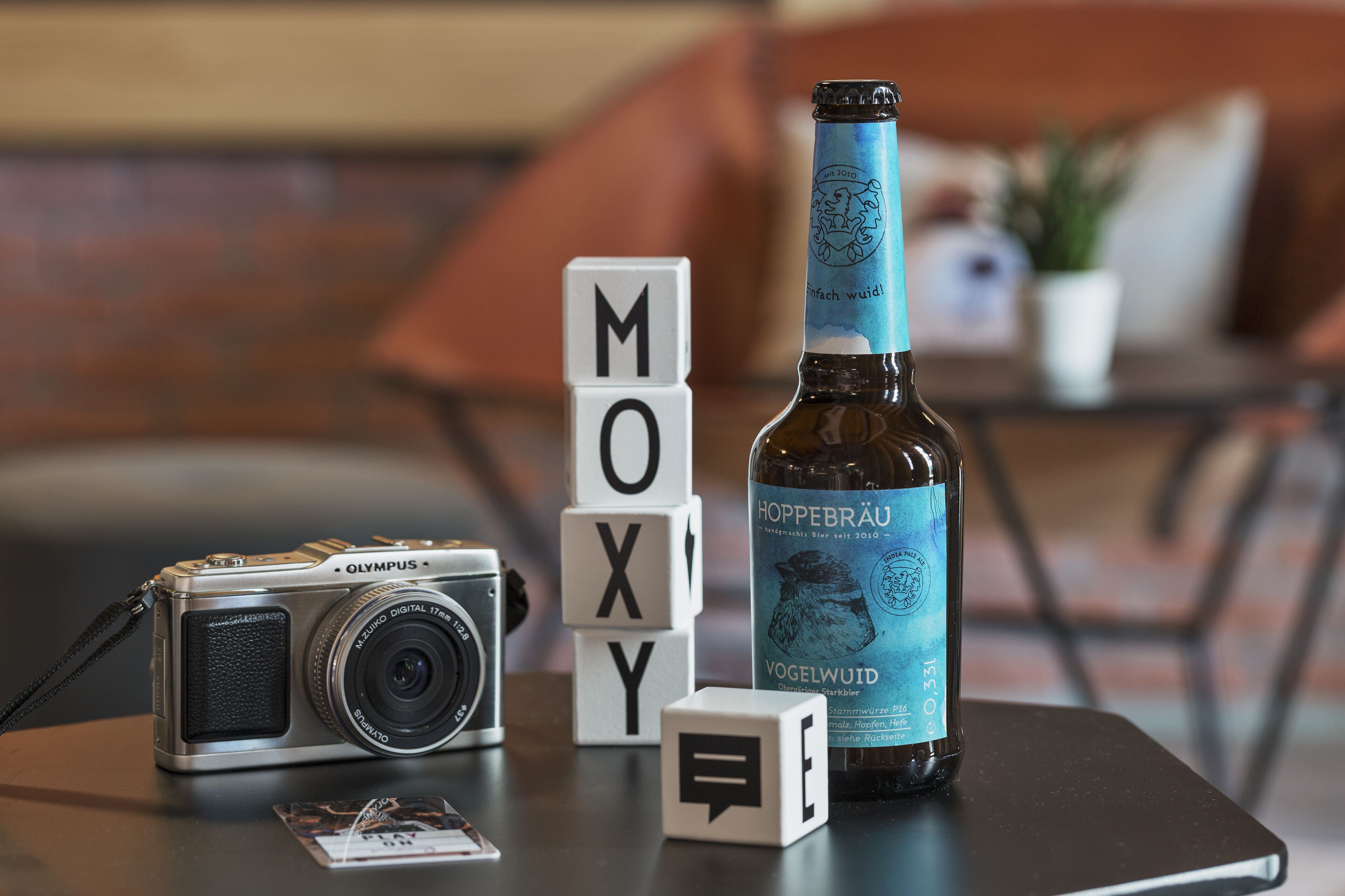 A camera, a bottle, and blocks with letters on a table.