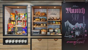 En avdelning med olika sorters förpackade snacks och en tavla där det står att ”The Munich Sky” serveras, tillsammans med en illustration av stadens silhuett.