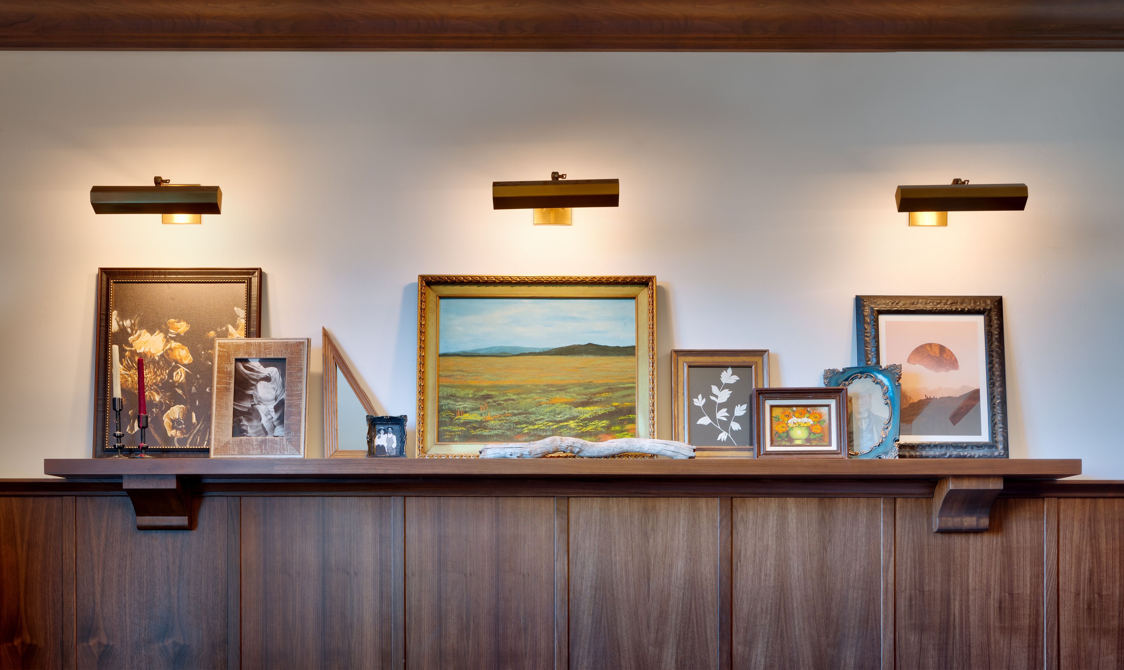 Un panel de exhibición con varias obras de arte enmarcadas y un panel de madera debajo.