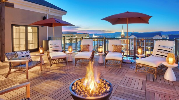 A rooftop terrace with a fire pit, lounge chairs, and umbrellas.