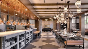 A spacious dining area with a checkered floor, multiple dining tables, and hanging pendant lights.