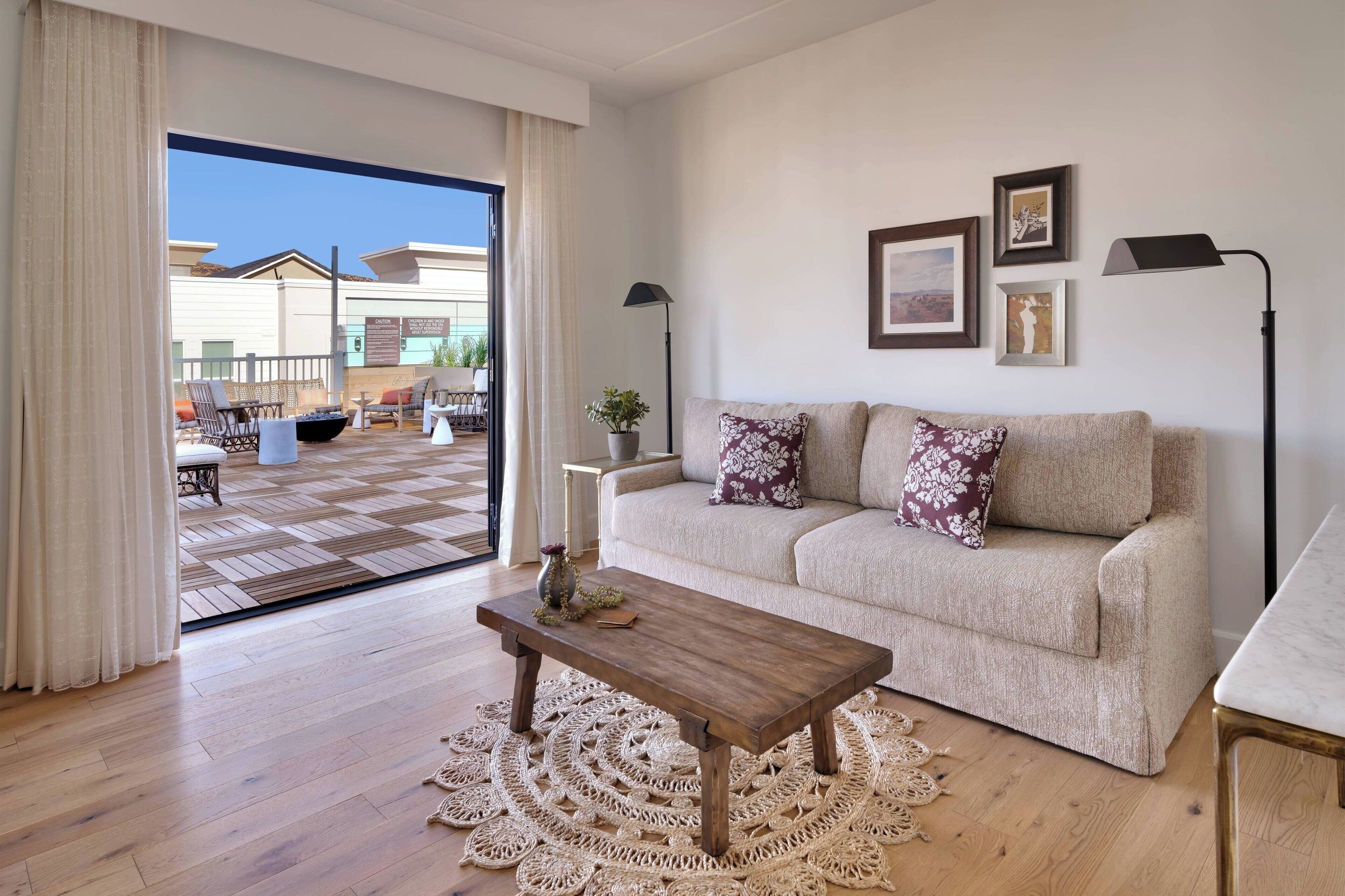 Un salon comprenant un canapé, une table basse et une vue sur une terrasse extérieure, accessible par une porte vitrée.