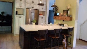 A kitchen with a central island, bar stools, and pendant lighting. - Maplehurst Manor B&B (Dorchester)