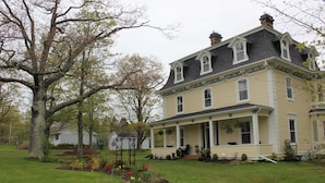 A large, two-story house with a porch and a garden. - Maplehurst Manor B&B (Dorchester)