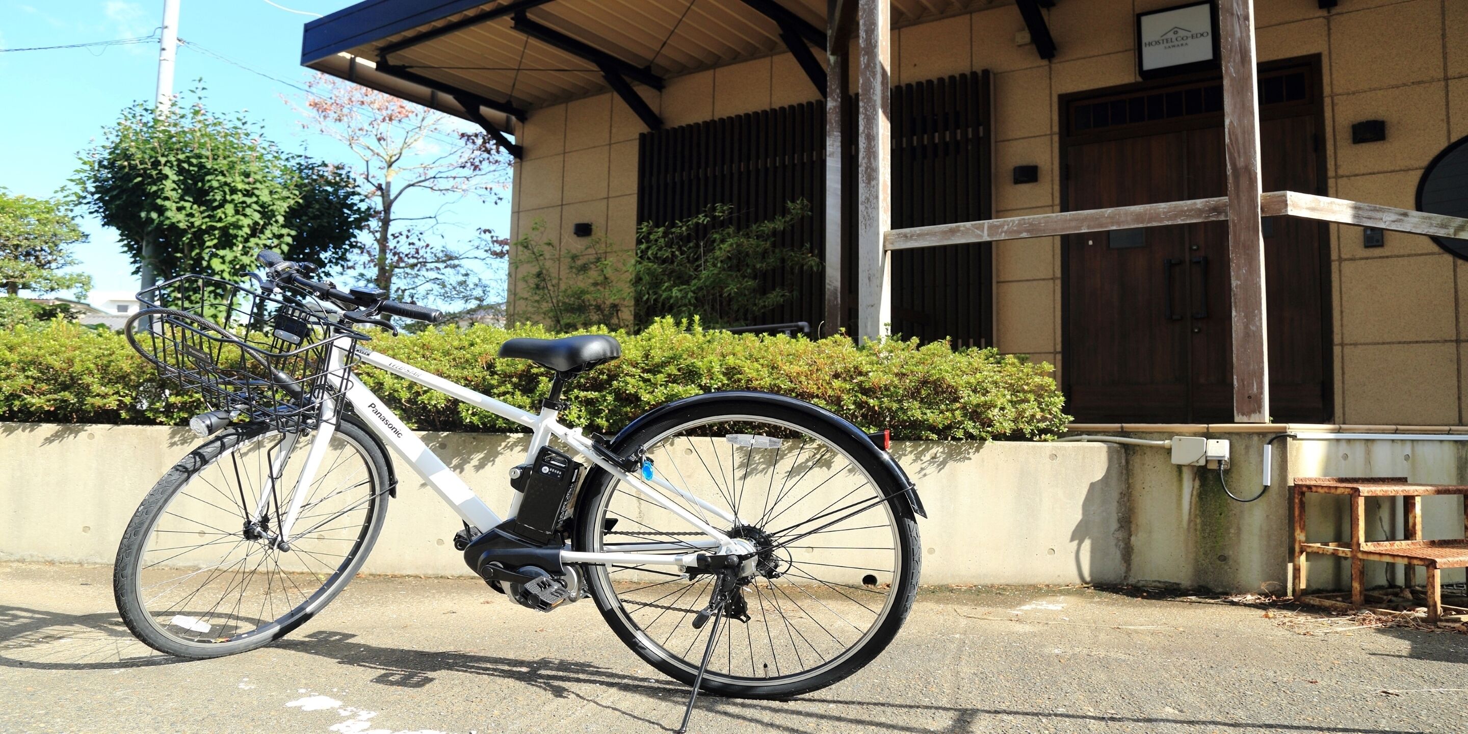 A white bicycle parked in front of a building with a sign that reads "HOSTEL COEDO".