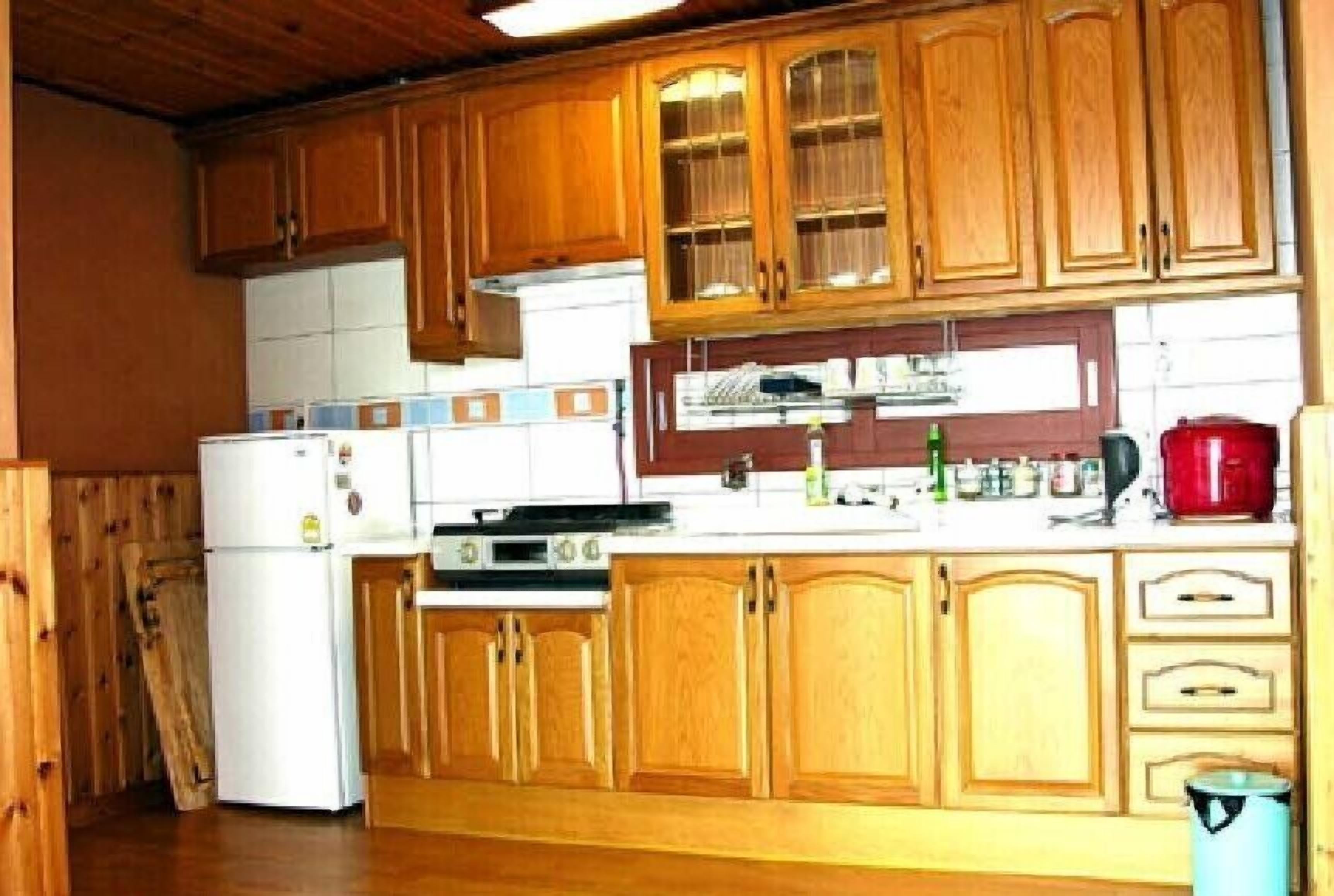 Eine Küche mit Holzausstattung, einem weißen Kühlschrank, einem Herd und einer roten Kaffeemaschine.