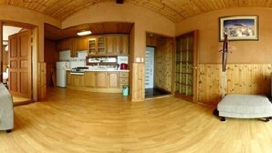 A spacious kitchen with wooden cabinets and a curved ceiling. - Jisakke Poongyeong Pension (Seogwipo)