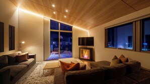 Una sala de estar moderna con chimenea, un sofá y un ventanal grande.