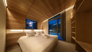 Un dormitorio moderno con una cama grande, lámparas de noche, vistas al exterior y techo de madera.